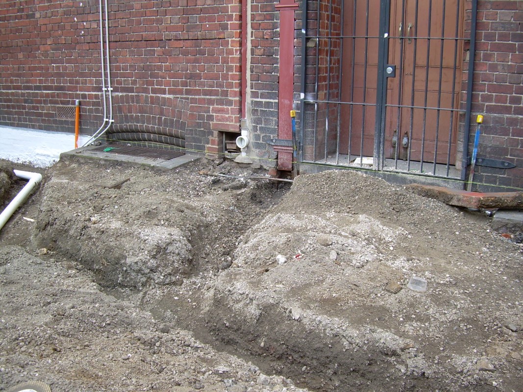 A channel is dug for pipes that will collects water from the downpipes and divert it into the system.